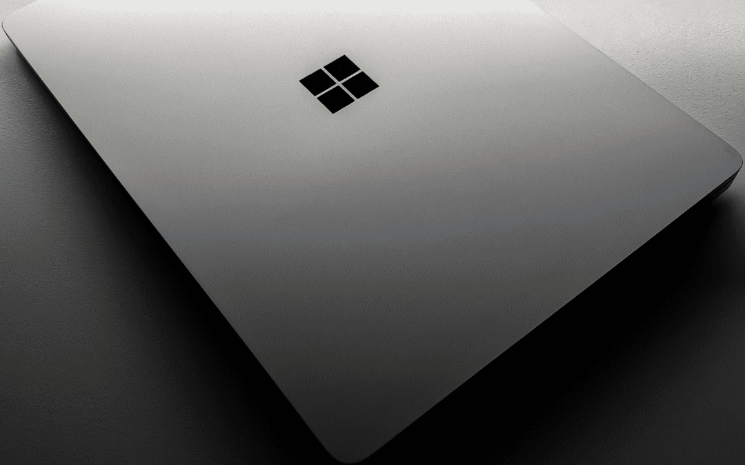 A silver laptop with the Microsoft logo in the center.